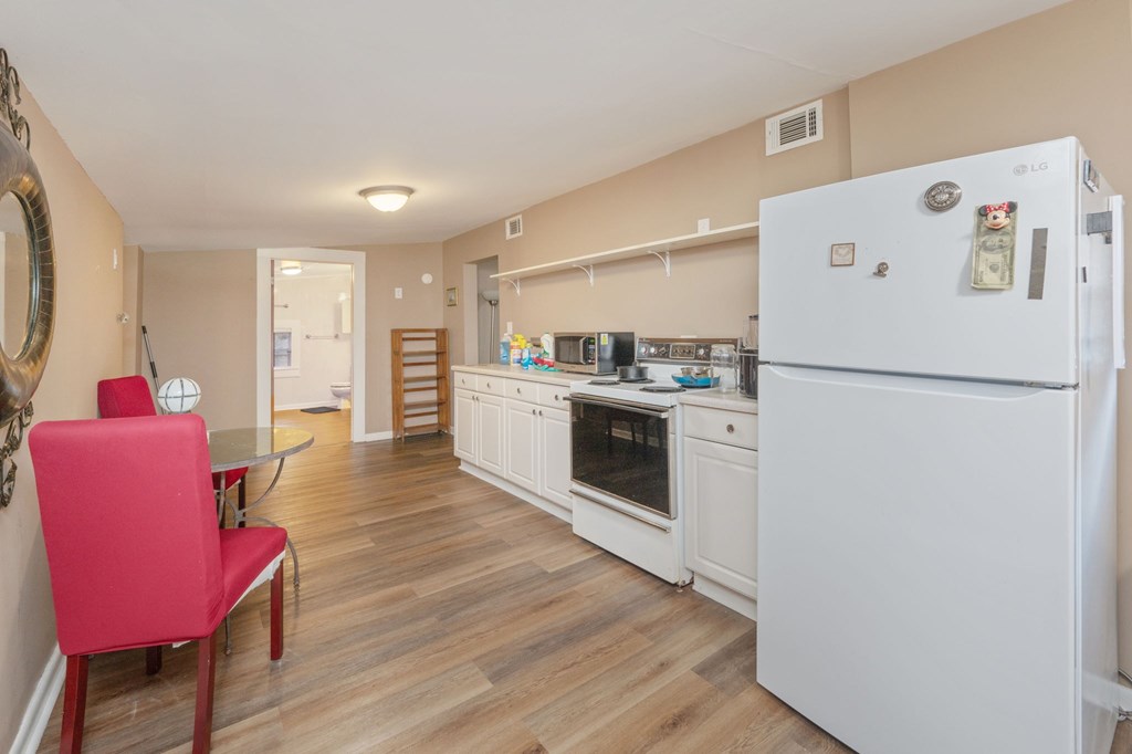 A kitchen with a white fridge and a red chair.