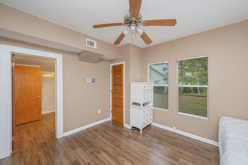 A room with a ceiling fan and a white refrigerator.