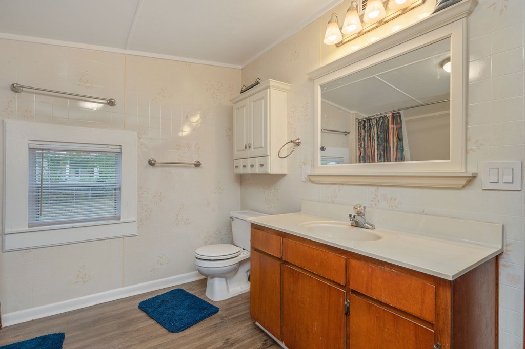 A bathroom with a toilet, sink, and mirror.
