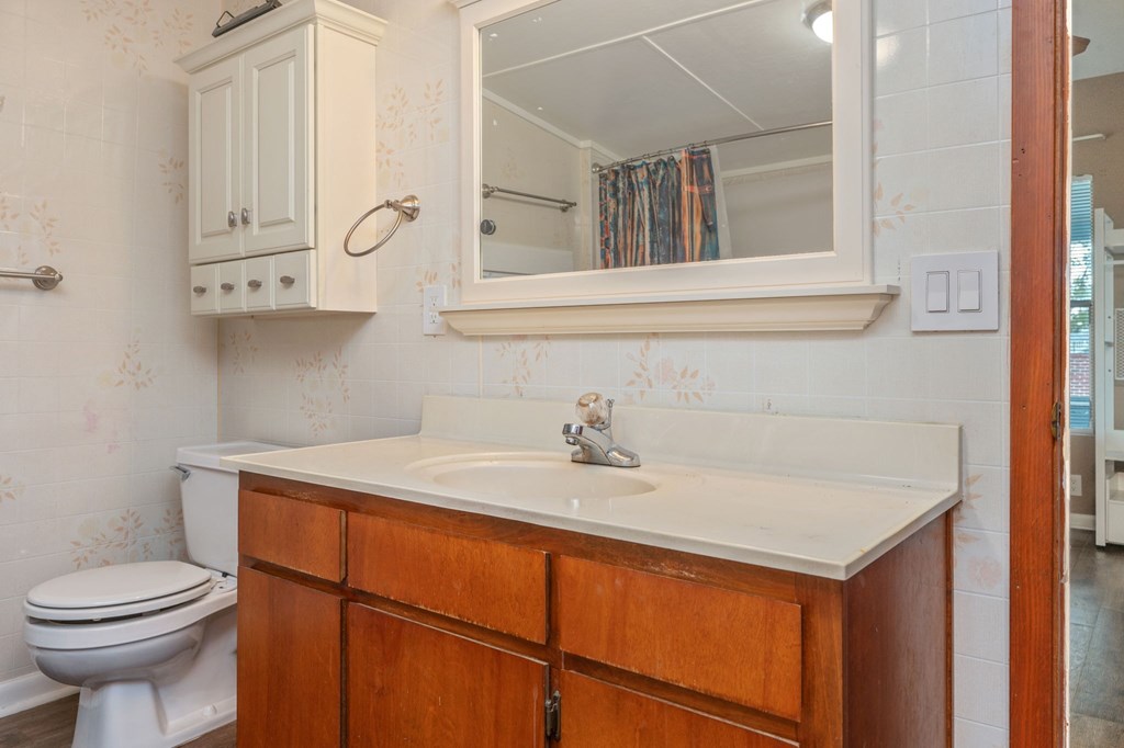A bathroom with a toilet, sink, and mirror.