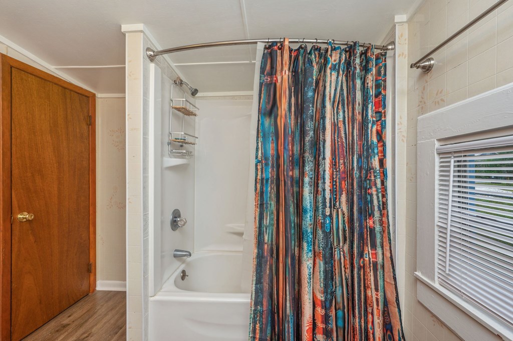 A bathroom with a white tub and a shower curtain with a pattern of blue, orange, and brown stripes.