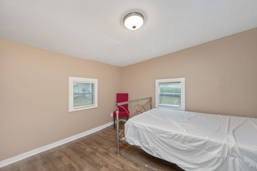 A bedroom with a bed, chair, and window.