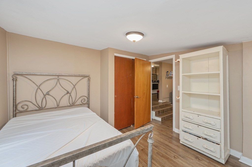 A bedroom with a bed, wardrobe, and a staircase.