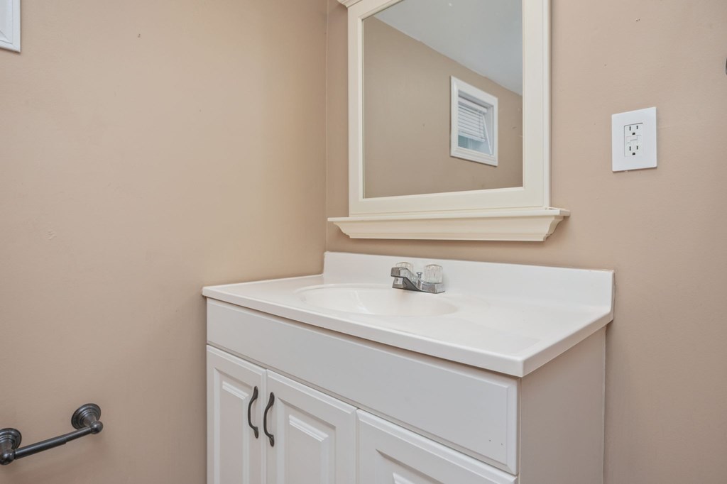 A white bathroom vanity with a mirror above it.