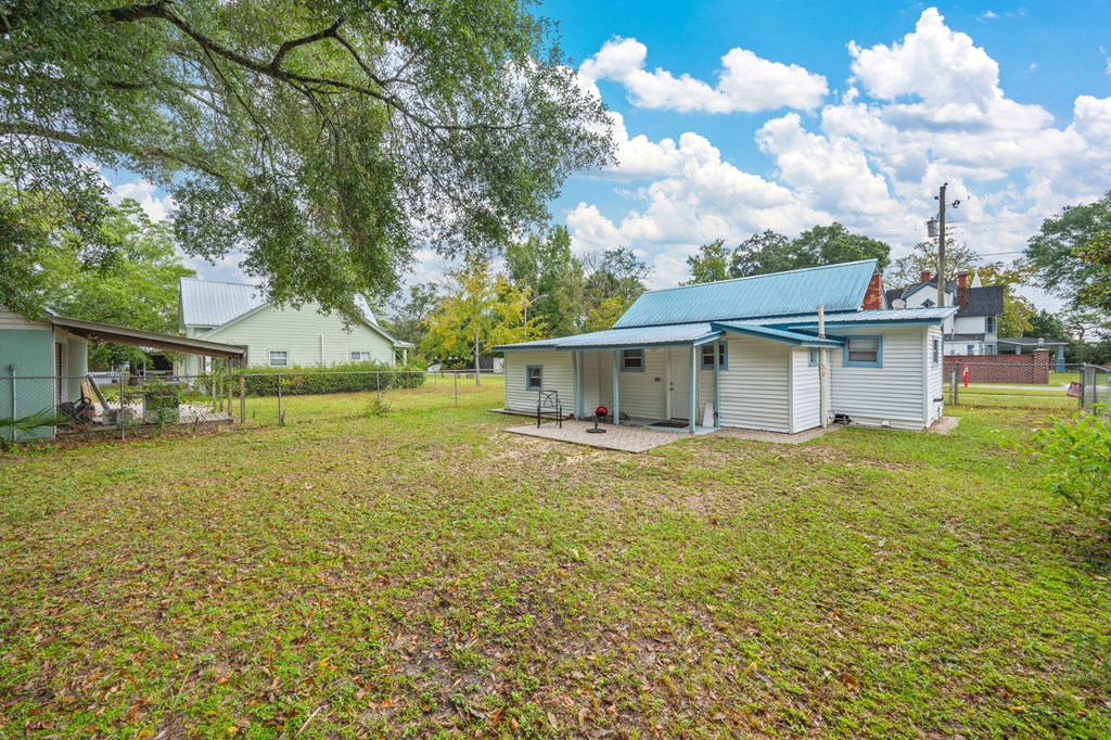 A white house with a blue roof is surrounded by a grassy field.
