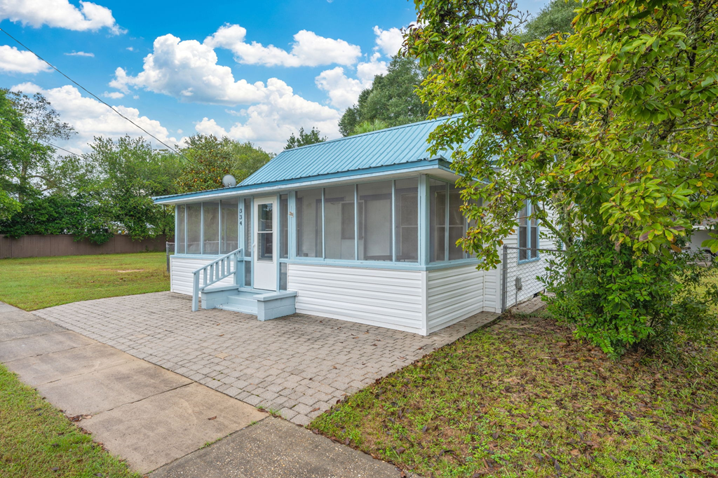 A small house with a porch and a green roof.