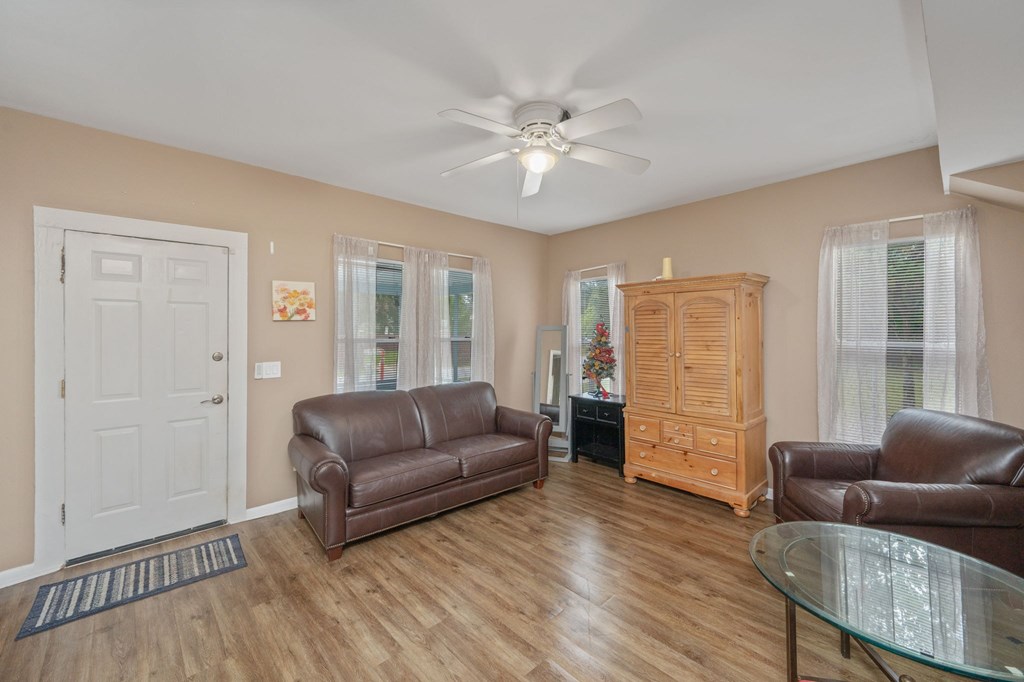 A living room with a brown leather couch, a glass table, and a wooden cabinet.