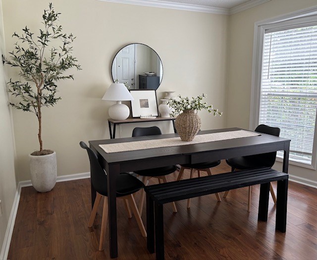 A dining room with a table, chairs, and a plant.