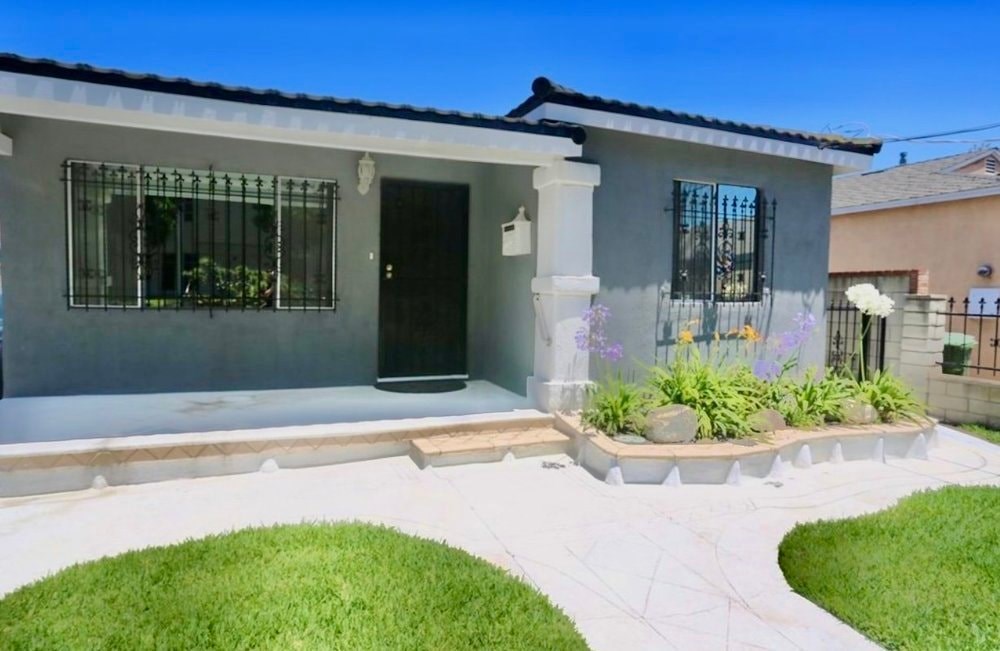A house with a white front yard and a black door.