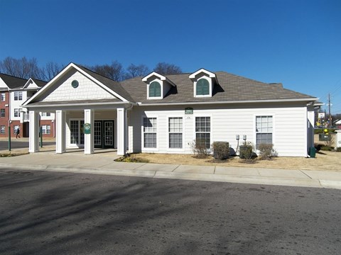 A white building with a brown roof and a green sign on the front.