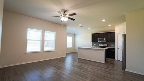 A spacious living room with a kitchen in the background.