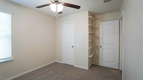 A room with a ceiling fan and built-in shelves.