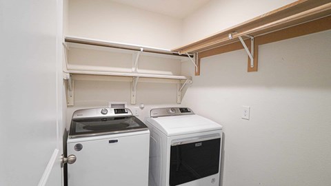 A white oven and microwave are installed under a shelf in a small room.
