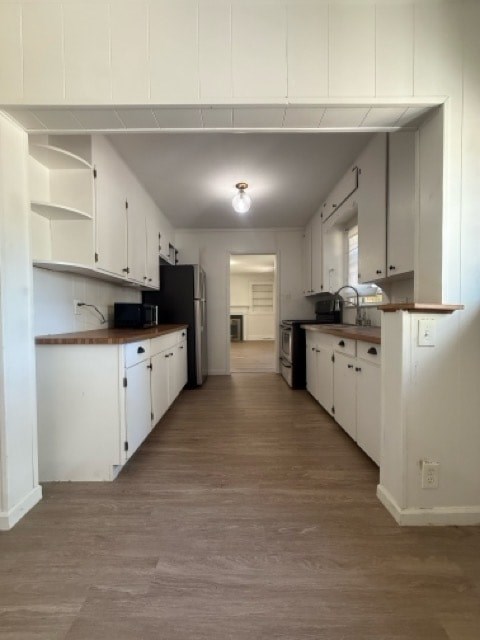 A kitchen with white cabinets and a black refrigerator.