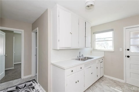 A white kitchen with a sink and cabinets.