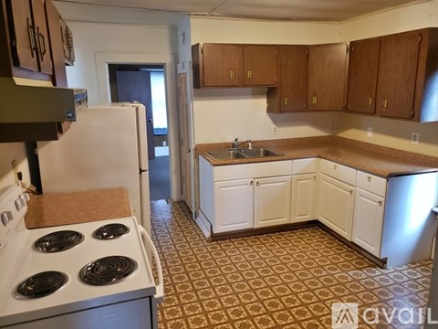 A kitchen with a white stove top oven and white cabinets.