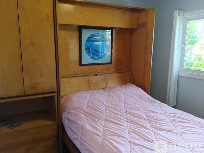 A bed with a pink comforter sits in a room with a wooden headboard and a picture of a globe on the wall.