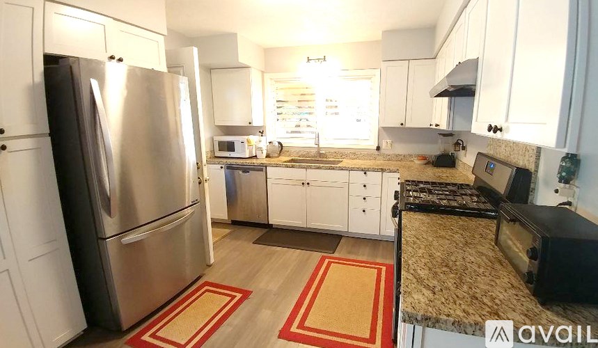 A kitchen with a black fridge and white cabinets.