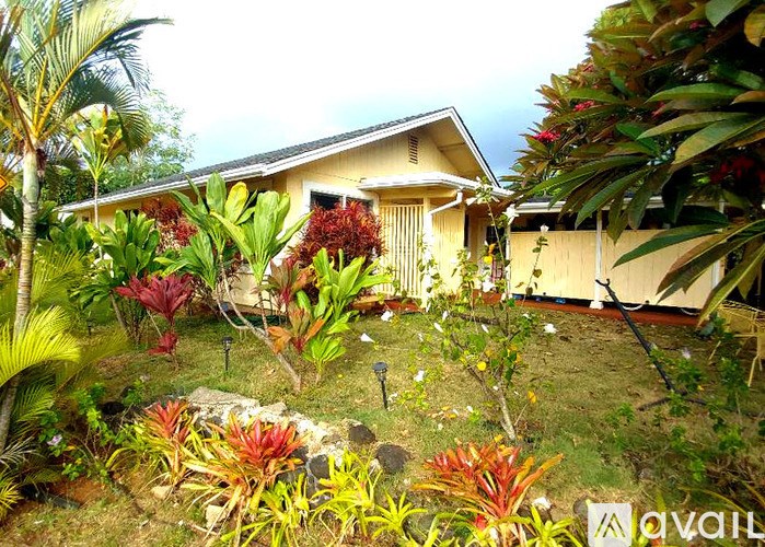 A tropical garden with a house in the background.