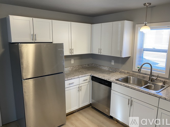 A kitchen with a stainless steel refrigerator, dishwasher, and white cabinets.