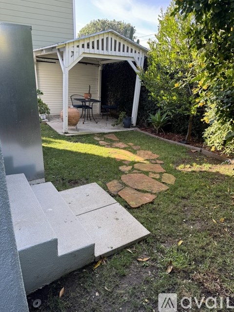 A backyard with a white pergola and a stone pathway.