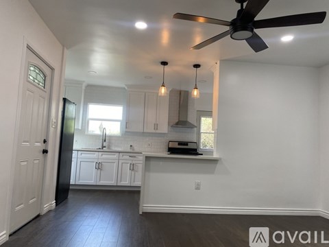 A kitchen with white cabinets and a black refrigerator.