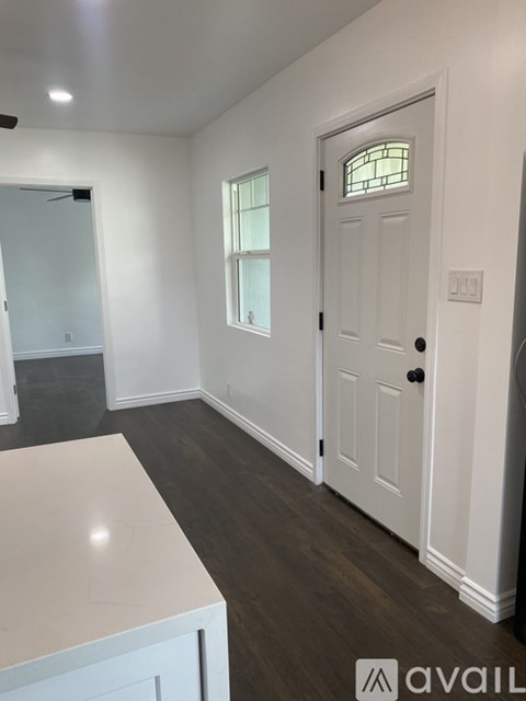 A white door with a glass window is in a room with white walls.