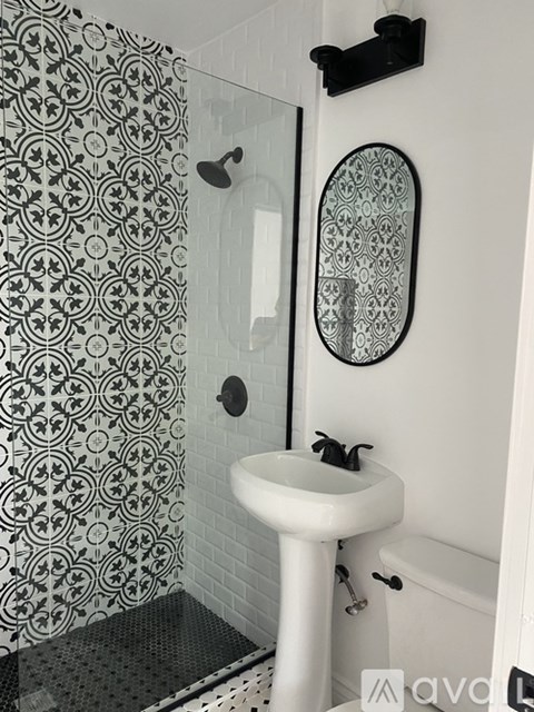 A bathroom with a white sink and a shower with a black and white shower curtain.