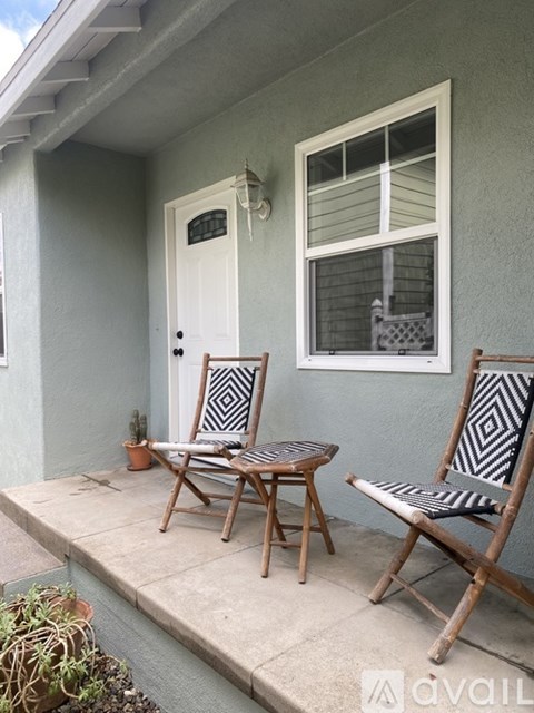 Two chairs and a table are on a porch.