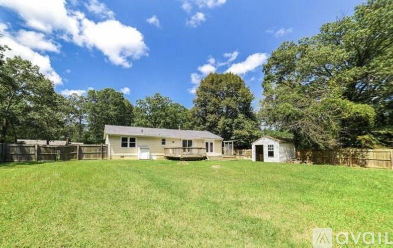 A house with a fence and trees in the background.