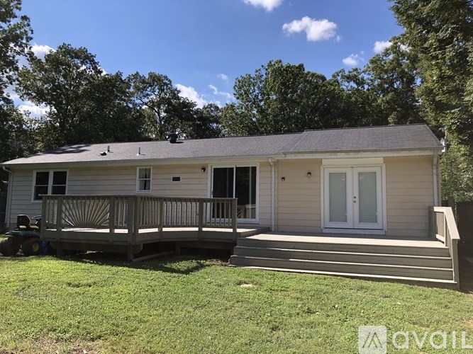 A house with a deck and a tree in the background.