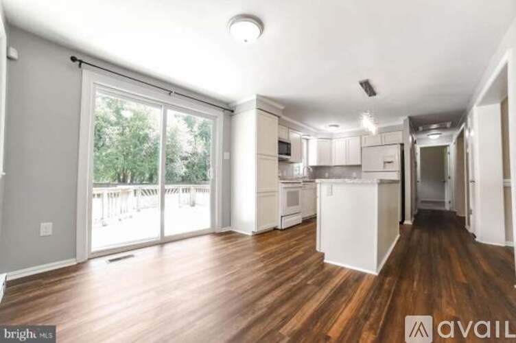 A spacious kitchen and living room with wooden floors and white cabinetry.