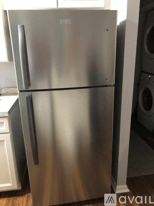 A stainless steel refrigerator with a freezer on top and a door to the left.
