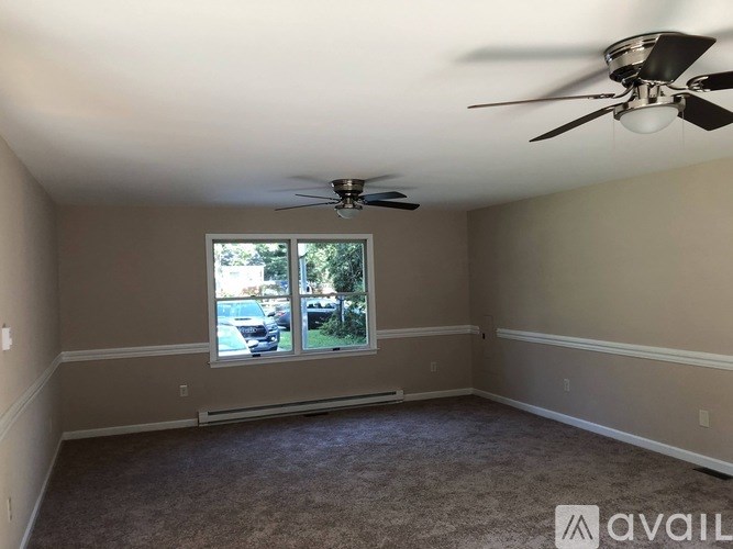 A room with a ceiling fan and a window overlooking a parking lot.
