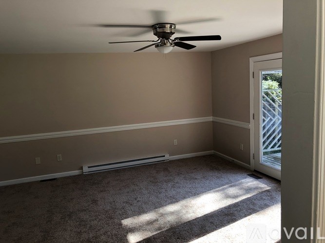 A room with a ceiling fan and a carpeted floor.