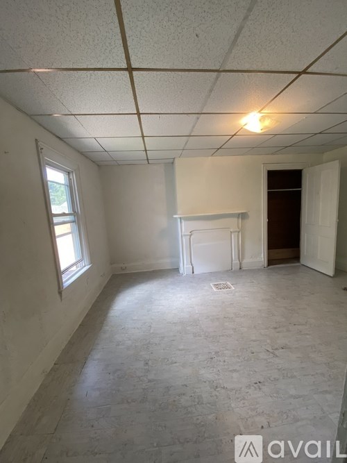 A room with a white fireplace and a window on the left side.