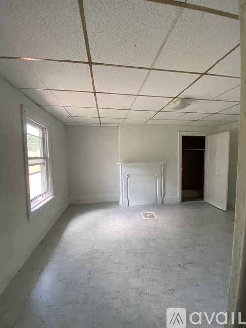 A room with white walls and a window on the left side.