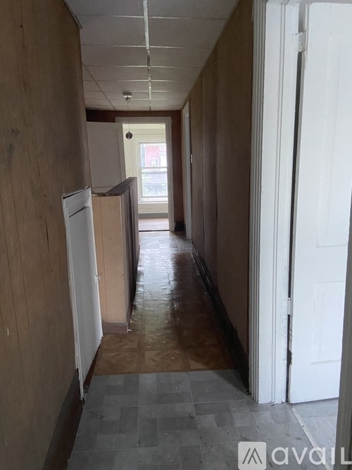 A long hallway with a white door on the right.