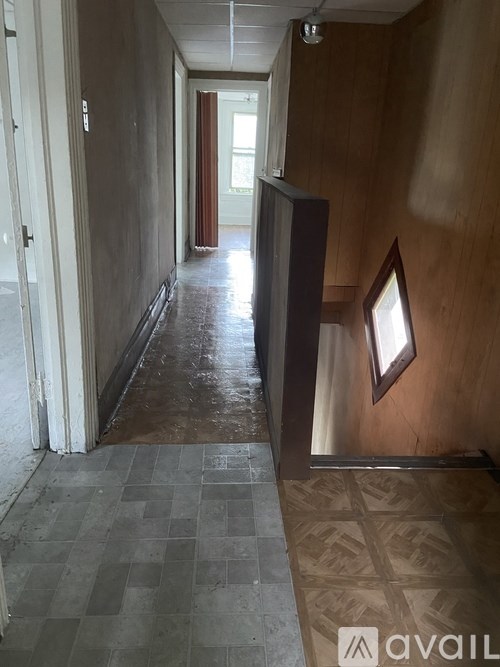 A long hallway with a tiled floor and a door at the end.