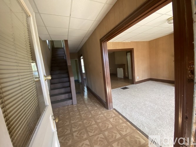 A hallway with a carpeted floor and a staircase.