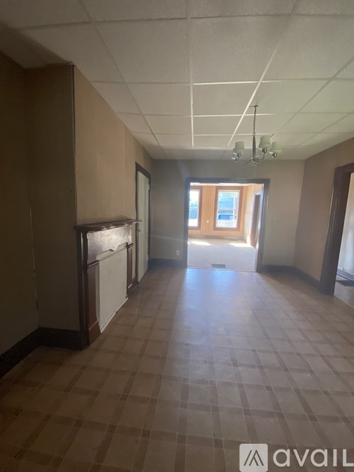A room with brown tiled flooring and a window letting in natural light.