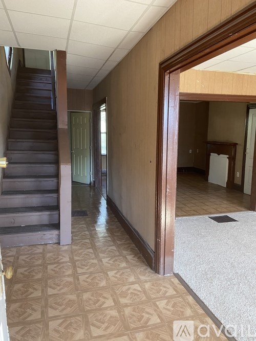A hallway with a staircase and a doorway leading to a kitchen.
