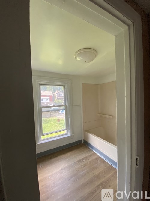 A room with a window and a wooden floor.