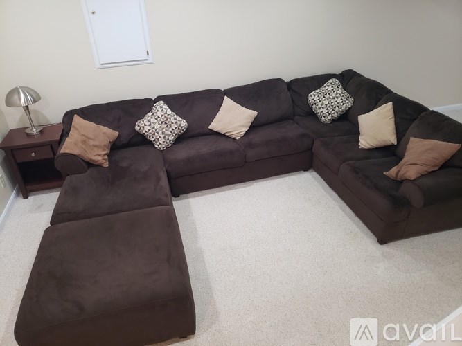A brown sectional sofa with pillows and a small end table.