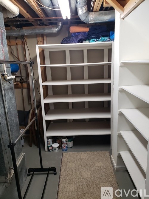 A white shelving unit is in a cluttered room.