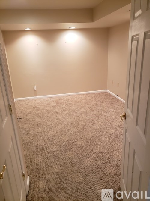 A carpeted room with a door on the left and a door on the right.