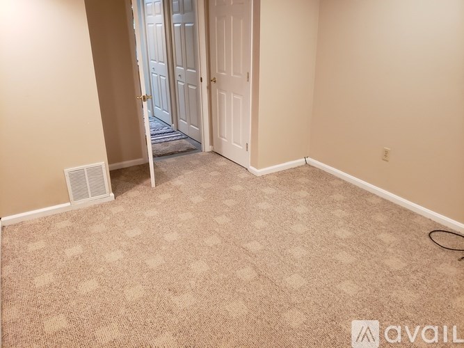 A room with a carpeted floor and a door in the background.