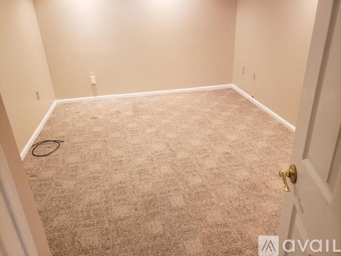 A room with a carpeted floor and a door on the right side.