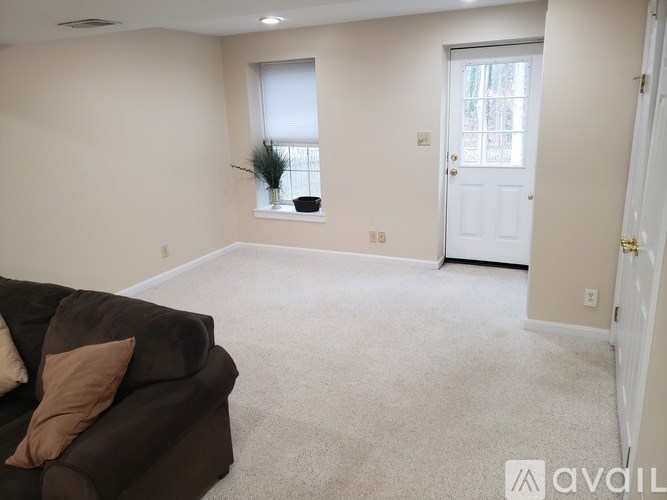 A living room with a brown couch and a window.