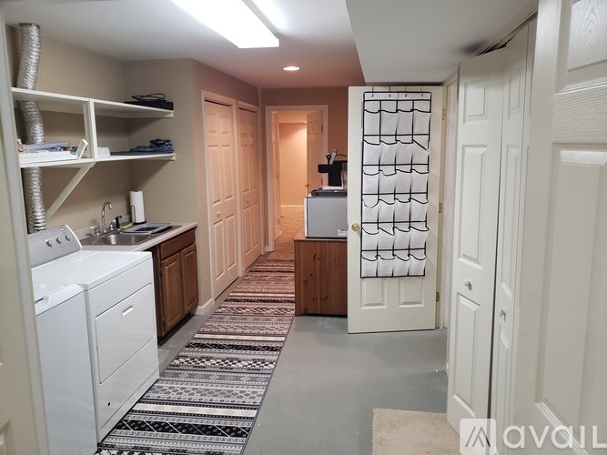 A laundry room with a washer and dryer, a sink, and a rug on the floor.
